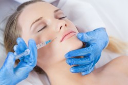 Surgeon making injection above lips on woman lying on operating table
