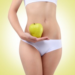 woman holding an apple with his hands near the belly