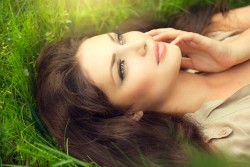 Beauty woman lying on the field and dreaming. Enjoying nature